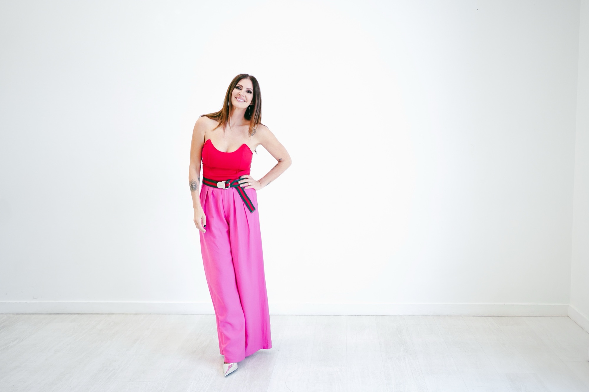 amy edwards in a red top and pink wide-leg pants, smiling